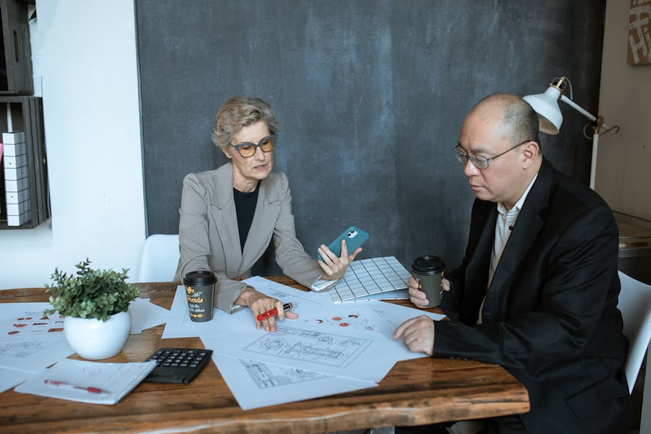 Two business professionals discuss project designs at an office desk