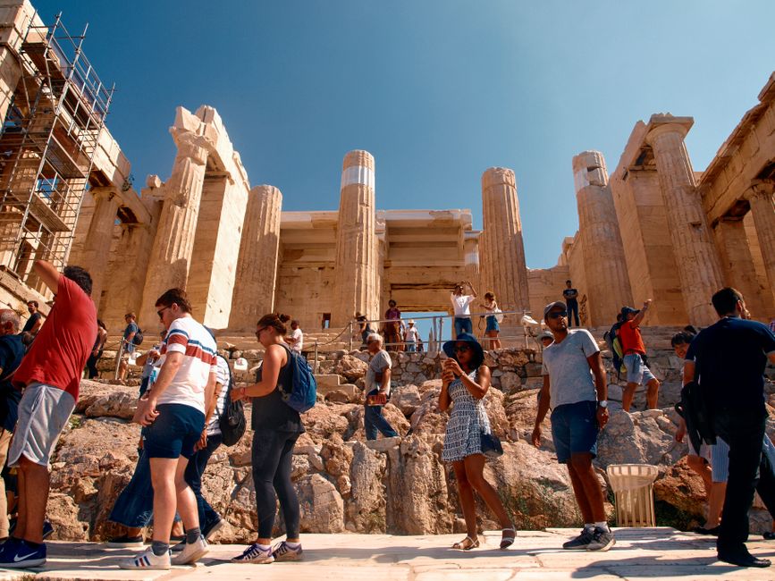 Gomile turista posjećuju antički Partenon u Ateni pod vedrim ljetnim nebom.